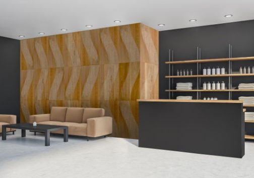 Corner of reception zone with light brown sofa and coffee table. White tiling wall. Wooden shelf with bathware and marble desk on the dark grey background. Concrete floor. 3d rendering